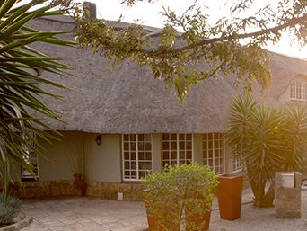 The thatched guest house and courtyard in late afternoon light.